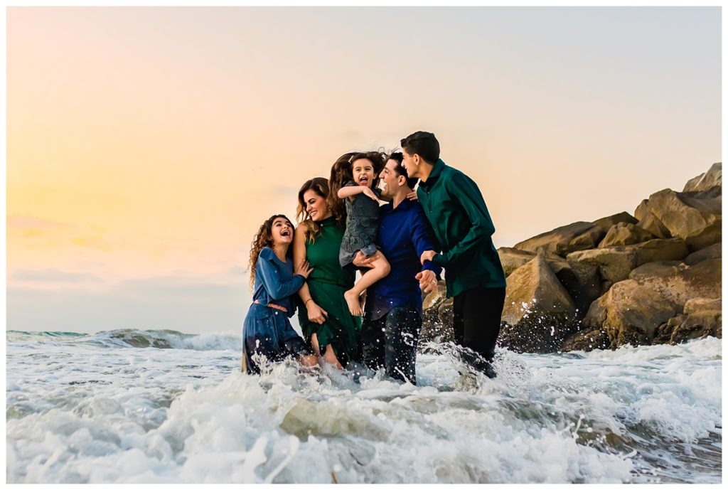 Family playing in the ocean during their portrait session at Ponto Beach in Carlsbad
