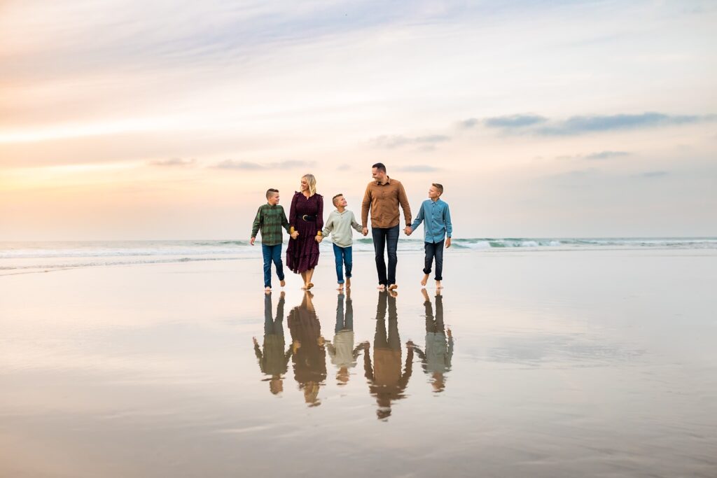 Family walking hand in hand on beach in Del Mar, CA