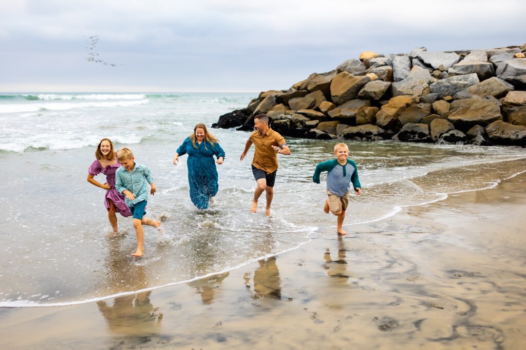 Family running together by the ocean in San Diego
