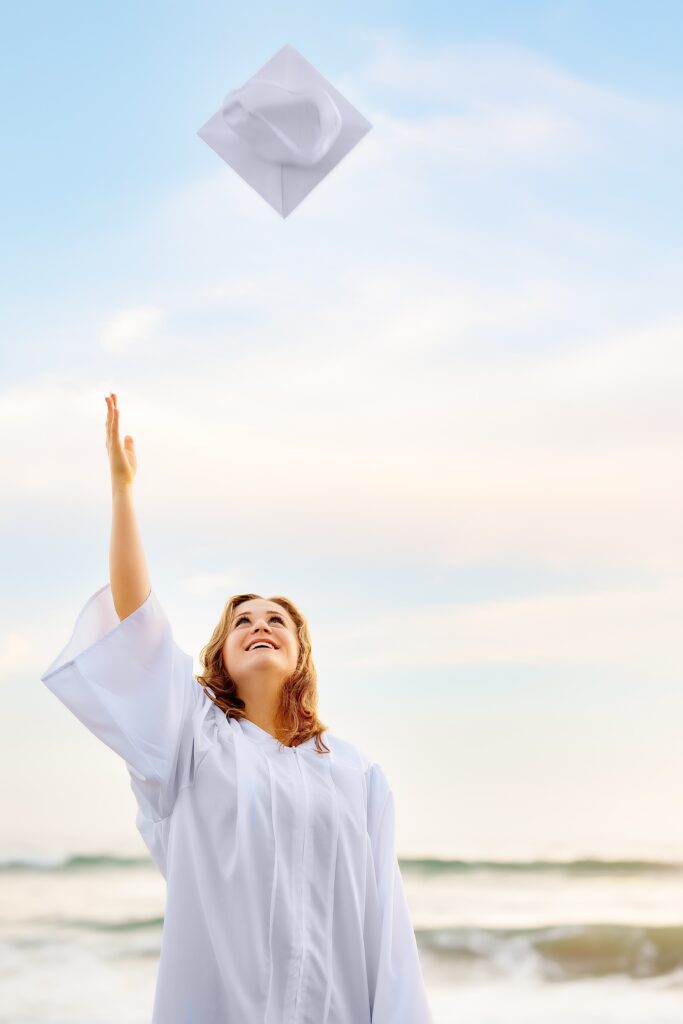 Senior Photography of teen girl throwing her graduation cap at the beach in San Diego